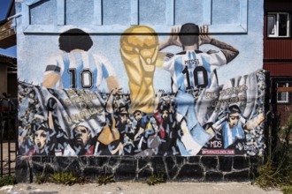 Diego Maradonna and Lionel Messi with the World Cup trophy on a house wall in Ushuaia, Argentina,