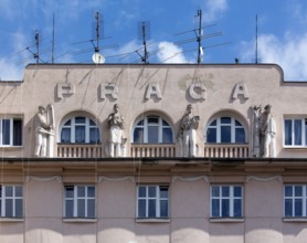 Praga Garage, figures with tools and machines on the façade