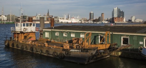 Hamburg harbour, working ship WASSERBAU I in front of wooden barracks, city skyline with museum