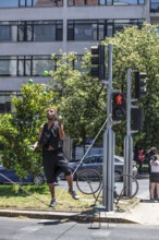 Street artist dances on a rope and juggles between two traffic lights, Santiago de Chile, Chile,