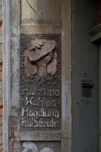 Advertising relief of a coal merchant, weathered left side of the portal Holz und Kohlenhandlung