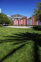 Cyclist in front of the Smith Centre with symphony installation Pipe Dream by Tim Bavington, Las