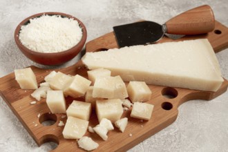 Freshly sliced and grated cheese, parmesan cheese, Gran gusto. Grana padano. on a wooden chopping