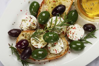 A plate with a snack, ciabatta bread with cheese and olives, olive oil, spices and herbs, top view,