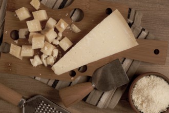 Freshly sliced and grated cheese, parmesan cheese, Gran gusto. Grana padano. on a wooden chopping