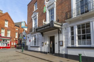 Doorman standing in entrance door of historic White Hart Hotel, Bailgate, city of Lincoln,