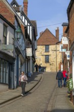 People walking up Steep Hill in winter, passing shops, Lincoln, Lincolnshire, England, UK