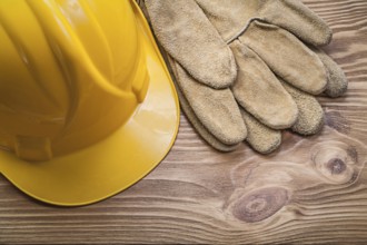 Building helmet leather protective gloves on wooden board construction concept