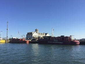 Fireboats on the banks of a river next to a historic building under a blue sky, chicago, usa