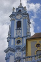 Baroque church tower with clock and richly decorated structures in blue and yellow, wachaus, donau,