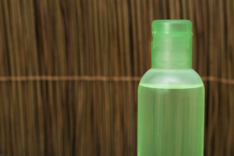 Green transparent cosmetic bottle. Wooden background