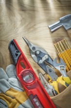 Assortment of construction tooling in leather tool belt on wooden board