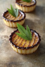 Three petite fruit tarts are displayed on a rough, textured surface. The focus is on the nearest