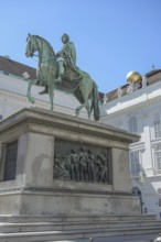 Bronze statue of a horseman on a decorated pedestal in front of a building, vienna, austria