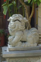 A decorative stone lion statue adorns the temple courtyard, penang, malaysia