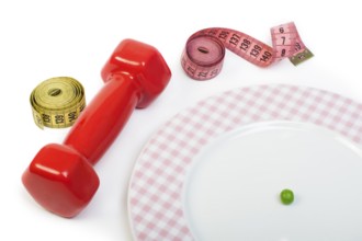 Plate with one peas. Dumbbell and centimetre measure. Studio shot