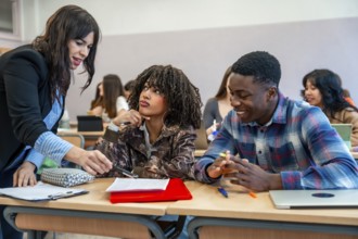 Professor explaining lesson to diverse university students sitting at desk, helping them with their