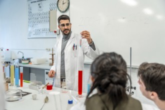 Chemistry teacher showing test tube with chemical reaction to students during experiment in