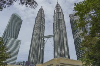 Two tall twin towers in an urban setting, framed by green vegetation, kuala lumpur, malaysia