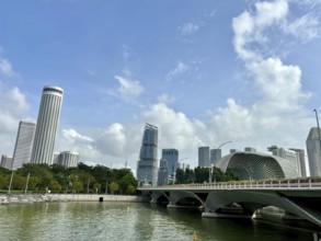 Modern skyscrapers and bridge on the riverside with blue sky and scattered clouds, singapore