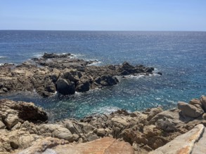 Rocky coastline with crystal clear water under a blue sky, cagliari, sardinia, italy