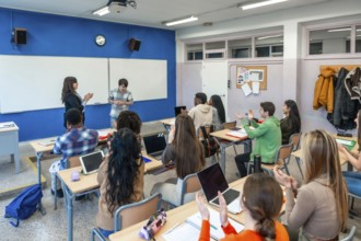 Multi ethnic university students clapping in classroom after a presentation of a shy student, with