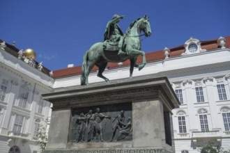 Bronze statue of a horseman on a pedestal in front of a historic building, vienna, austria