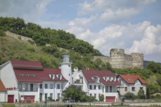 White houses with red roofs and a tower in front of an old castle on a hill, donau, austria