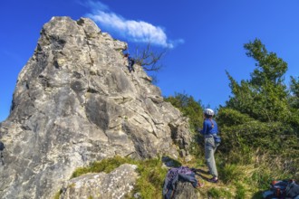 Two female rock climbers scaling a challenging cliff face, enjoying a sunny day in nature