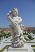 Stone sculpture of a child with a cornucopia full of fruit in front of a historic building,