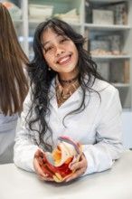 Smiling medical student holding anatomical model of female reproductive organs during anatomy class