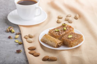 Traditional arabic sweets (basbus, kunafa, baklava) and a cup of coffee on a gray concrete