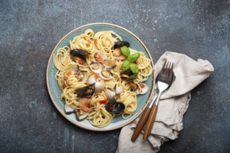 Italian seafood pasta spaghetti with mussels, shrimps, clams in tomato sauce with green basil on