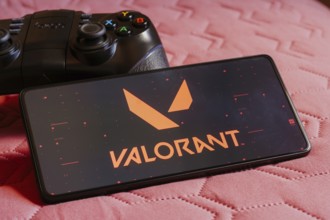 In this photo illustration, the Valorant logo is displayed on a smartphone screen, next to a