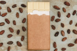 Scattered cocoa beans with white chocolate bar grunge background