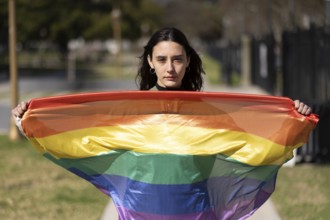 Lesbian girl holding LGBT flag looking seriously at camera