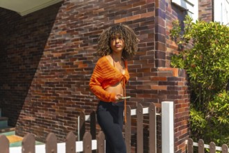Beauty brunette woman leaving the house while using mobile phone in a sunny day