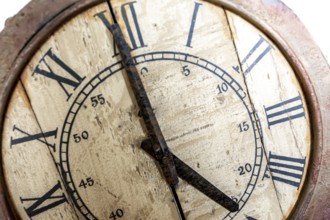 Old vintage and retro analogue clock displaying five o' clock. Worn-out and grunge style with