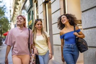 Happy diverse women walking and shopping along a modern city