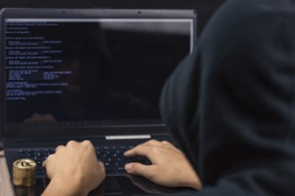 Dangerous hooded hacker on laptop breaks computer security sistem and steal bitcoin cryptocurrency