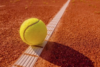 Yellow tennisball on the line at a clay court