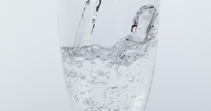 Water being poured into Glass against White Background
