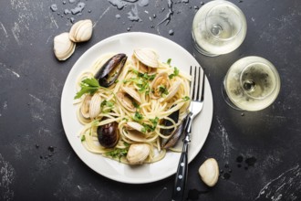 Spaghetti vongole, Italian seafood pasta with clams and mussels, in plate with herbs and two