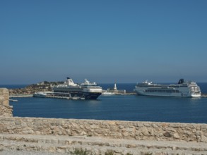 Cruise ships in the harbour with stone wall in the foreground under a clear blue sky, ibiza,