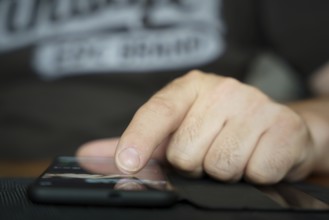 A person's fingers operate a smartphone lying on the table and w
