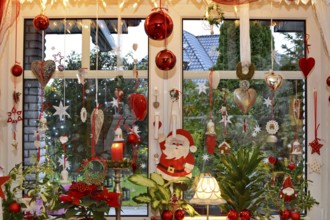 Christmas decorated window with fairy lights, Christmas balls, hearts, stars, bells, candle, Santa