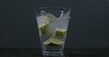 Green Citrus (citrus aurantifolia), falling into a Glass of Water
