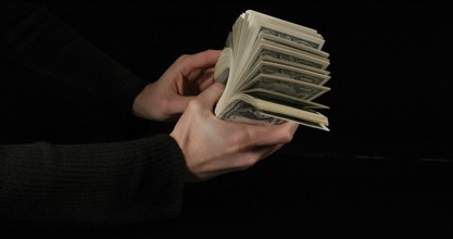 Hand of Woman and Dollar Bank Notes against Black Background