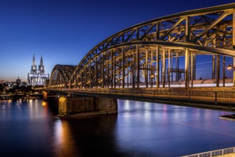 Twilight scene of the illuminated railway bridge with Cologne Cathedral in the background,