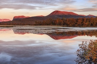 Mountains reflected in lake, autumn colours, cloudy mood, morning light, dawn, Nikkaluokta,